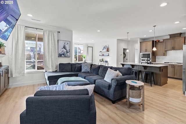 living room featuring light wood-type flooring, visible vents, and recessed lighting