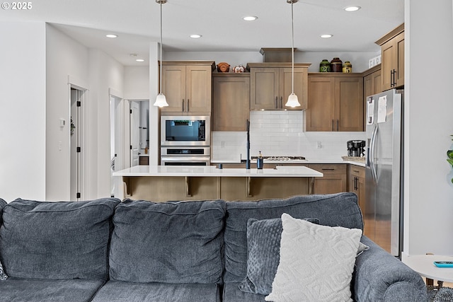 kitchen with stainless steel appliances, open floor plan, and light countertops