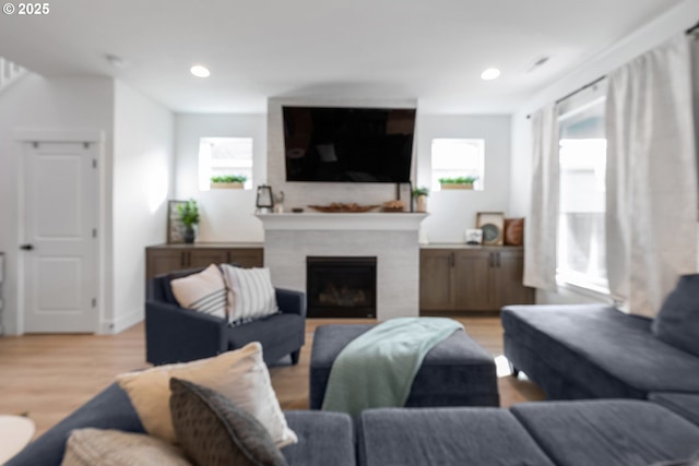 living area featuring light wood-type flooring, a fireplace, and recessed lighting