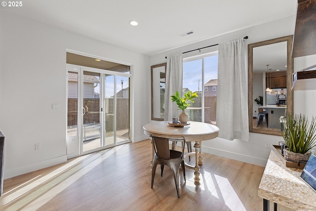 dining space with light wood-type flooring, baseboards, and visible vents