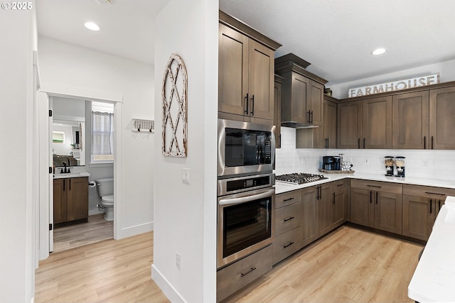 kitchen featuring light wood-style floors, tasteful backsplash, appliances with stainless steel finishes, and light countertops