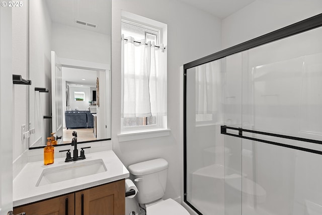 bathroom featuring toilet, a stall shower, vanity, and visible vents