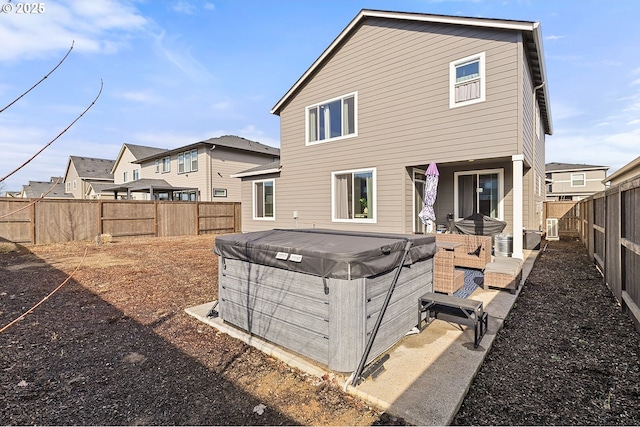 back of property featuring a fenced backyard and a hot tub