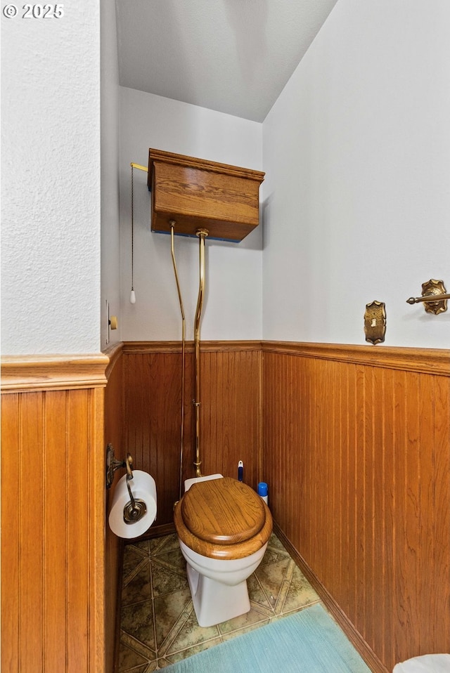 705 Prefontaine Dr, Coos Bay, OR 97420 - bathroom with toilet, a wainscoted wall, wooden walls, and tile patterned flooring