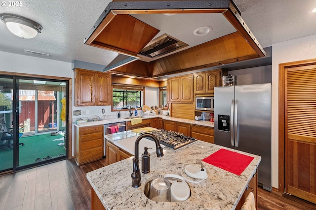 705 Prefontaine Dr, Coos Bay, OR 97420 - kitchen with stainless steel appliances, dark wood-type flooring, brown cabinets, a center island, and a textured ceiling