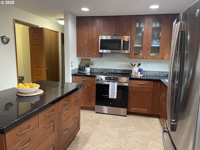 kitchen with recessed lighting, stainless steel appliances, brown cabinetry, light tile patterned floors, and glass insert cabinets