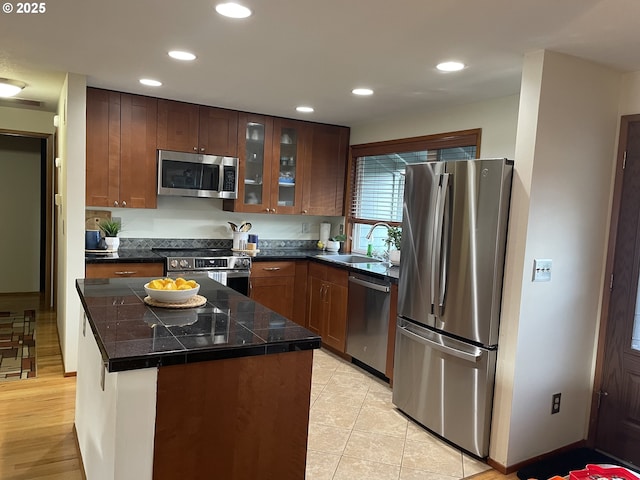 kitchen with a sink, a center island, recessed lighting, stainless steel appliances, and glass insert cabinets