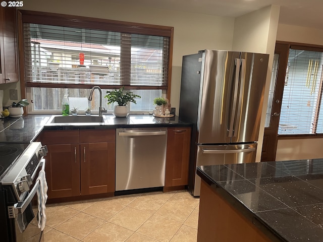 kitchen featuring light tile patterned floors, a healthy amount of sunlight, stainless steel appliances, and a sink