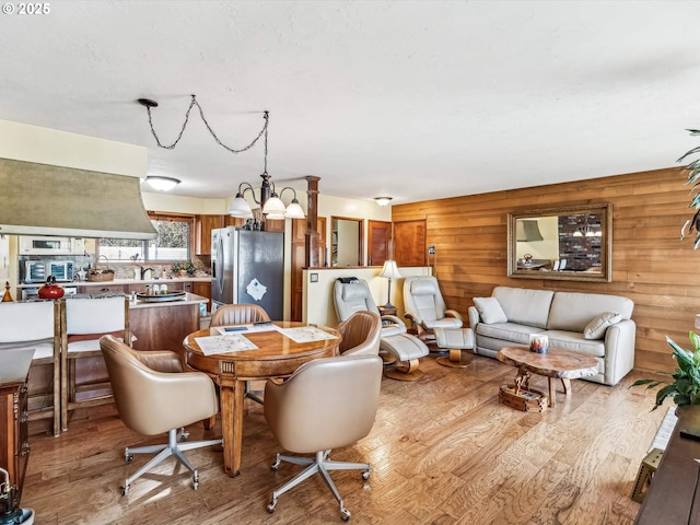 dining area featuring a notable chandelier, wooden walls, and light wood-type flooring