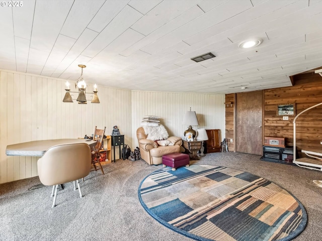 living area with carpet floors, a notable chandelier, and wood walls