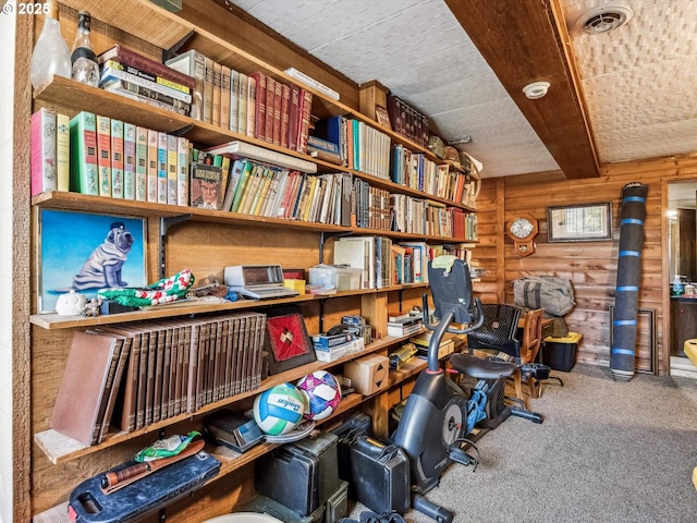 interior space with beamed ceiling, carpet floors, and wooden walls