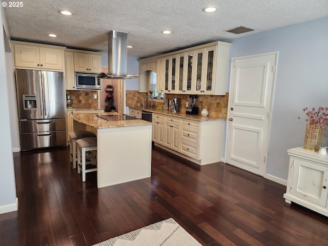 kitchen with visible vents, light stone counters, dark wood-style floors, stainless steel appliances, and island range hood