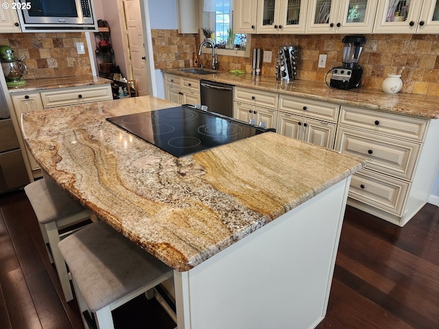 kitchen featuring a sink, stainless steel microwave, a kitchen island, dishwashing machine, and cooktop