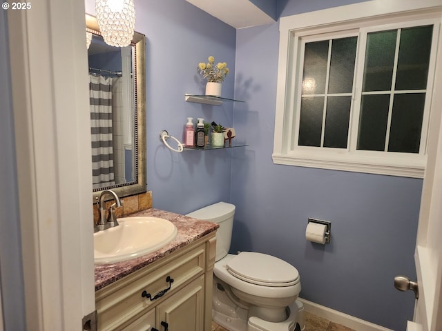 bathroom with a shower with curtain, toilet, an inviting chandelier, baseboards, and vanity