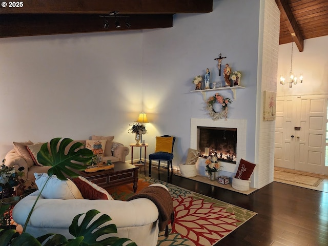 living room featuring beam ceiling, high vaulted ceiling, wood finished floors, a lit fireplace, and an inviting chandelier