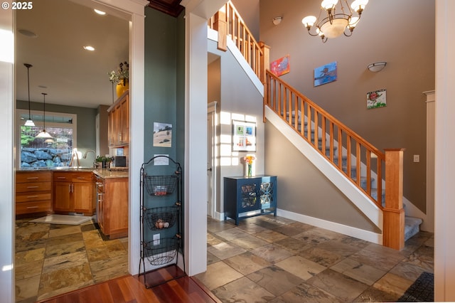 stairway with a high ceiling, stone tile flooring, baseboards, a chandelier, and recessed lighting