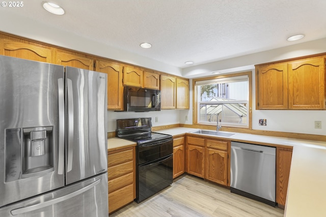 kitchen featuring light hardwood / wood-style floors, sink, a textured ceiling, and black appliances