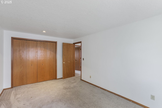 unfurnished bedroom with light colored carpet, a closet, and a textured ceiling