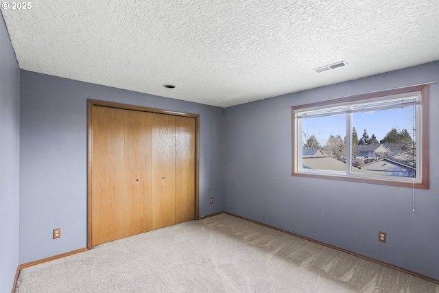 unfurnished bedroom featuring light carpet, a closet, and a textured ceiling