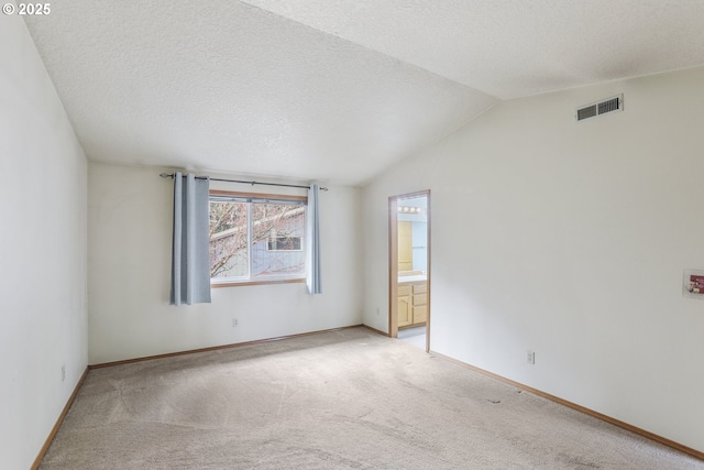 spare room featuring lofted ceiling, light carpet, and a textured ceiling