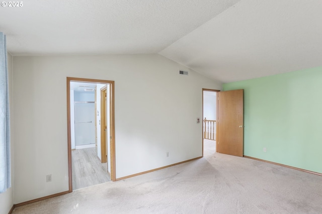 carpeted spare room featuring vaulted ceiling