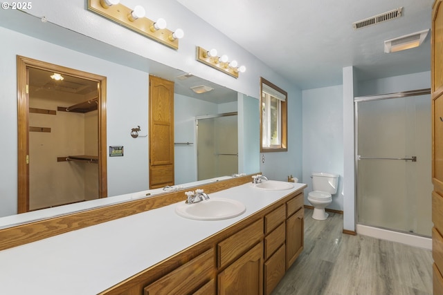 bathroom featuring vanity, wood-type flooring, a shower with door, and toilet