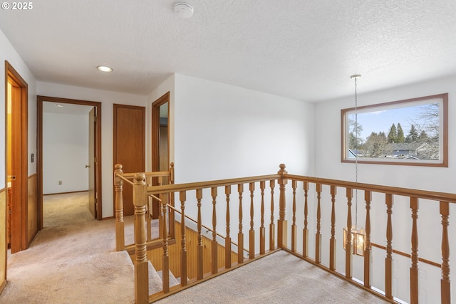 corridor with light colored carpet and a textured ceiling