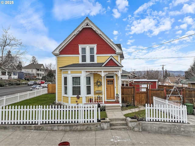 victorian-style house with a fenced front yard and a front yard