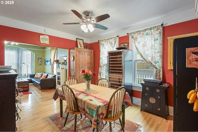 dining room with light wood finished floors, ceiling fan, and baseboards