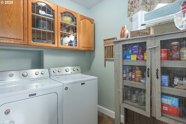 clothes washing area with baseboards, cabinet space, and washer and dryer