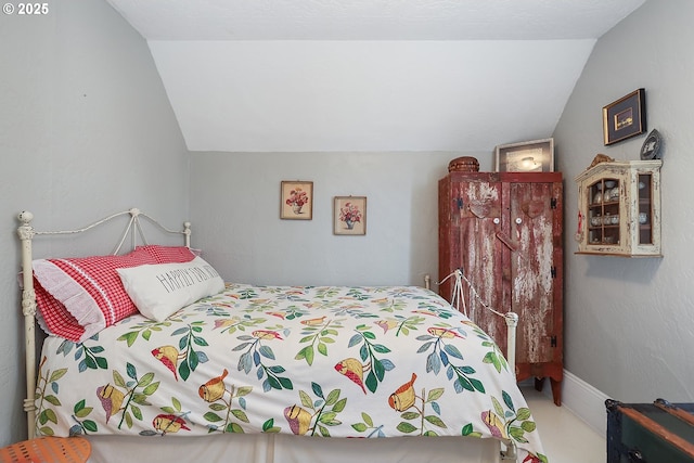 bedroom with lofted ceiling and baseboards