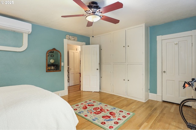 bedroom featuring a wall unit AC, light wood-style flooring, and baseboards