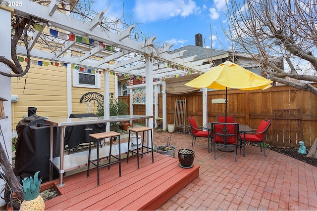 wooden deck featuring outdoor dining space, a patio area, fence, and a pergola