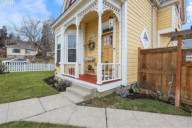 view of exterior entry featuring fence and a yard