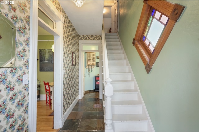 stairs with stone finish floor, baseboards, and wallpapered walls