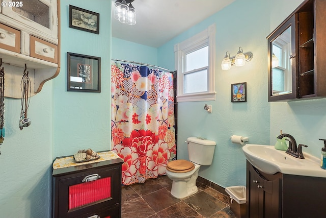 bathroom featuring a shower with curtain, baseboards, vanity, and toilet