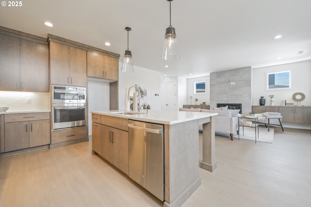 4308 N 12th Way, Ridgefield, WA 98642 - kitchen featuring a sink, appliances with stainless steel finishes, a tiled fireplace, and light wood-style flooring