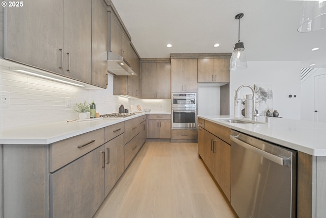 4308 N 12th Way, Ridgefield, WA 98642 - kitchen featuring appliances with stainless steel finishes, a sink, light wood finished floors, under cabinet range hood, and recessed lighting