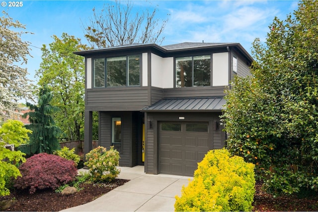 contemporary home with concrete driveway, an attached garage, a standing seam roof, and metal roof