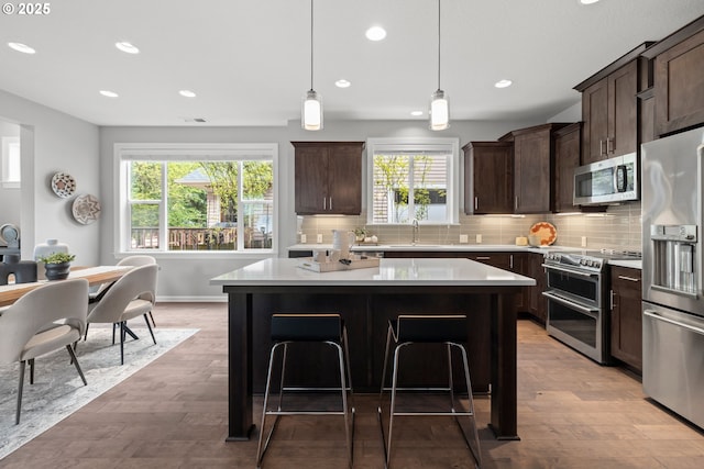 kitchen featuring a sink, appliances with stainless steel finishes, a kitchen island, and dark brown cabinets