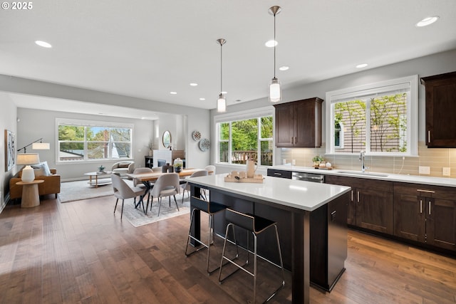 kitchen featuring a center island, dark brown cabinets, a sink, light countertops, and open floor plan