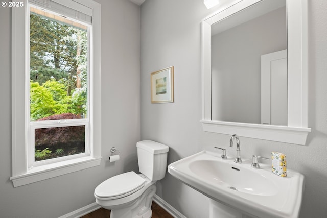 bathroom with toilet, baseboards, and a sink