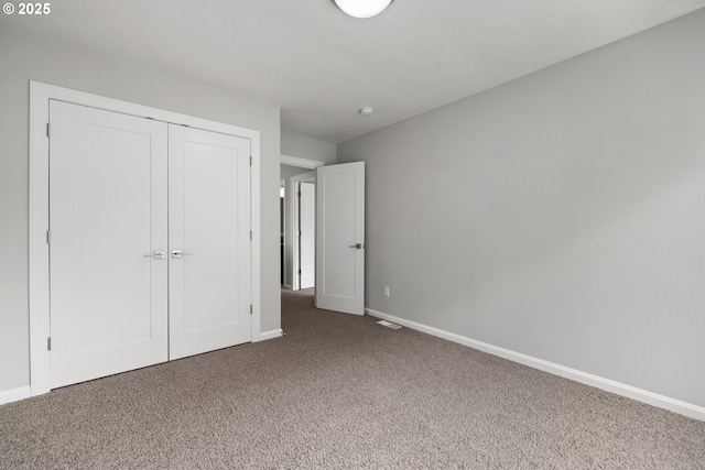 unfurnished bedroom with a closet, baseboards, and carpet flooring