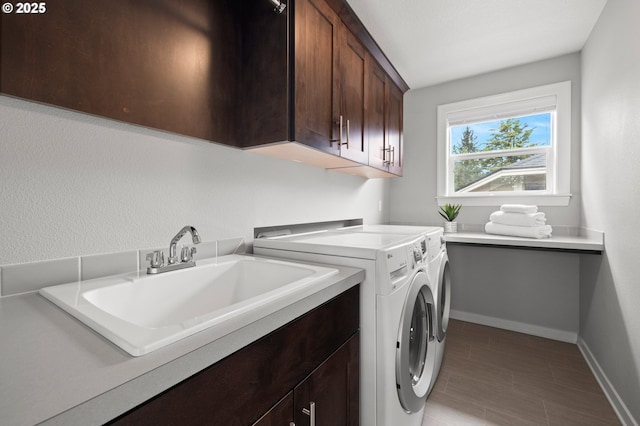 washroom with baseboards, a sink, cabinet space, and washing machine and clothes dryer