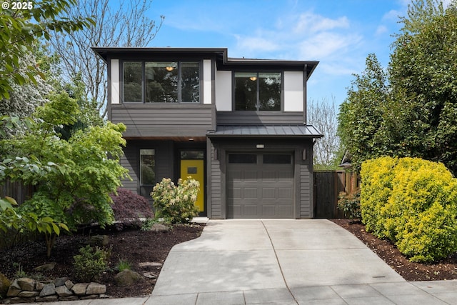 contemporary house with fence, metal roof, a standing seam roof, concrete driveway, and an attached garage