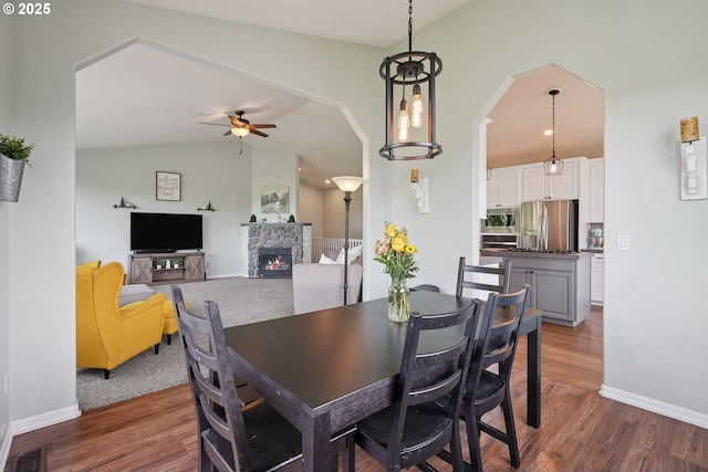 16117 SE Goosehollow Dr, Damascus, OR 97089 - dining room featuring ceiling fan, a fireplace, wood finished floors, vaulted ceiling, and arched walkways