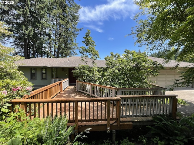 wooden deck with concrete driveway and an attached garage