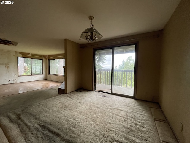 carpeted empty room featuring a chandelier
