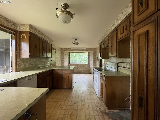kitchen featuring white appliances, a peninsula, and light countertops