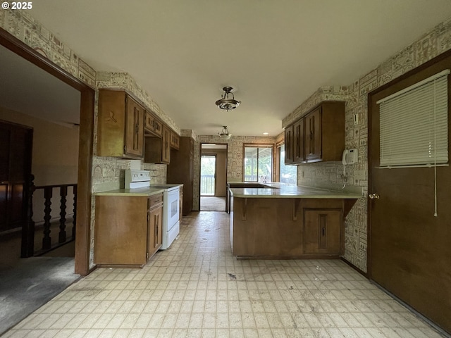 kitchen with white electric range, a peninsula, light flooring, light countertops, and a breakfast bar